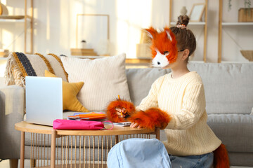 Quadrober girl in cat disguise doing homework at home