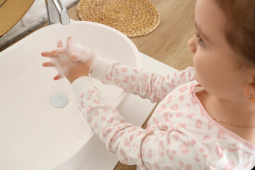 Little girl washing her hands near sink in bathroom, closeup