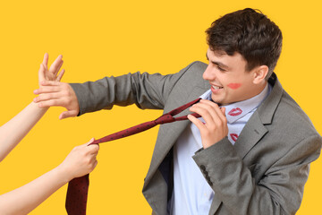 Angry wife scolding her husband after betrayal on yellow background