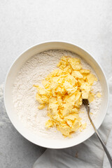 Overhead view of cold butter flour and sugar being mixed to make tart dough in a mixing bowl, process of making tart and pie shell or crust