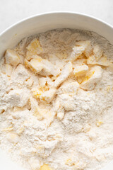 Overhead view of cold butter flour and sugar being mixed to make tart dough in a mixing bowl, process of making tart and pie shell or crust