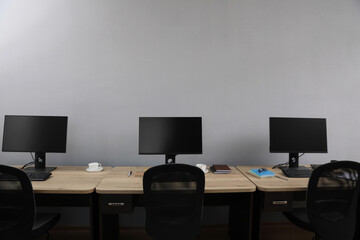Open office interior. Modern workplaces with computers near light grey wall