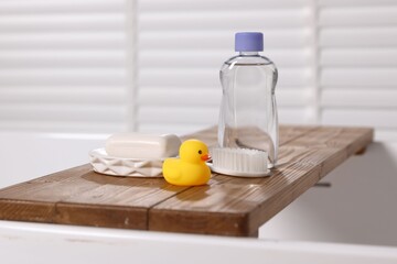 Baby bath accessories on wooden tray in bathtub indoors, closeup
