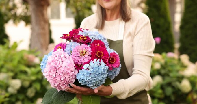 Senior woman with beautiful bouquet of flowers in garden, closeup
