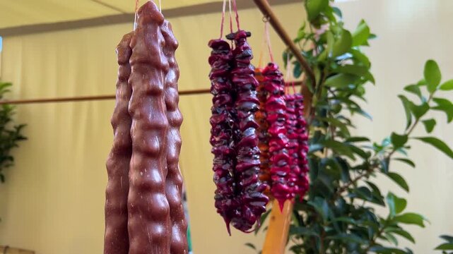 Horizontal 4K video. Georgian dish red, brown churchkhela hanging on rope. City holiday Tbilisoba, New Year market, autumn harvest fair, pastry shop, Christmas festival. National cuisine, sweet food