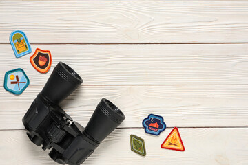 Naklejka premium Set of scout badges and binoculars on white wooden background with space for text