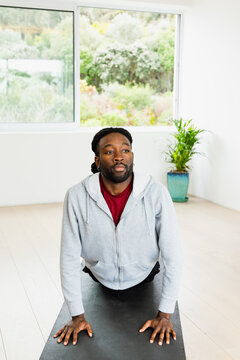 African American man in workout clothes bending backward on black mat by studio window, copy space