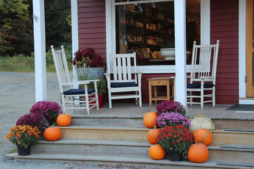 country style porch with white chairs and fall decoration of pumpkins and mums on the stairs