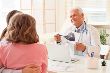 Obraz premium Male fertility doctor showing sonogram image to lesbian couple after IVF in clinic