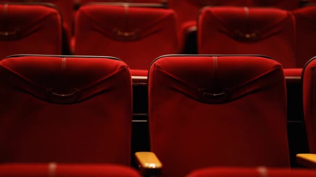 Classical theater inside. Rows of empty red velvet chairs in the opera house. Beautiful dramatic hall with vacant seats.