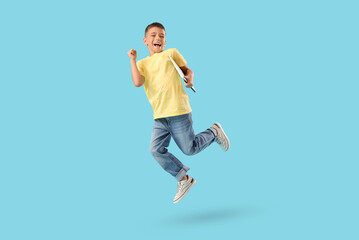 Obraz premium Little boy with laptop jumping on blue background