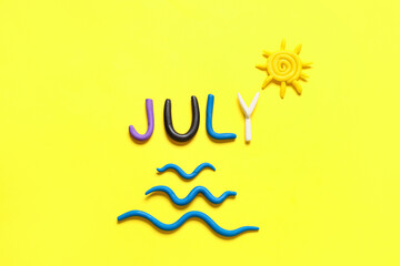 Word JULY made of play dough on yellow background