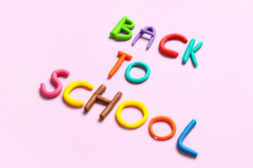 Text BACK TO SCHOOL made of play dough on pink background