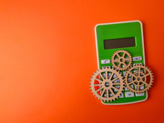 The image displays a green calculator accompanied by three wooden gears on an orange background