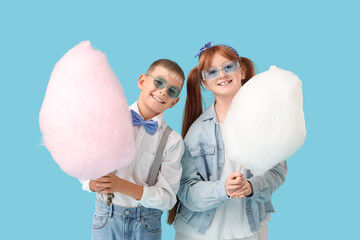Teen girl and boy with cotton candy on blue background
