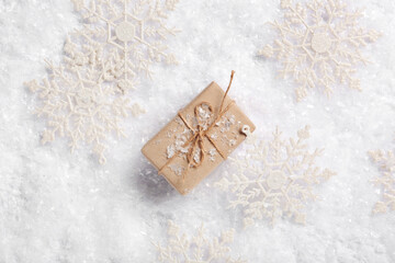 Composition with decorative snowflakes and gift box on snow as background, closeup