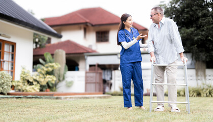 A friendly female nurse assists an elderly man who is using a walker in the front yard of a house. The scene depicts compassionate and professional home healthcare