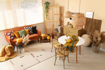 Interior of living room with sofa, table and pumpkins near window