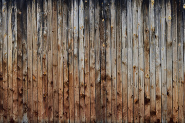 Vertical wood board background severely weathered. Blackish, grayish and brownish wooden wall.