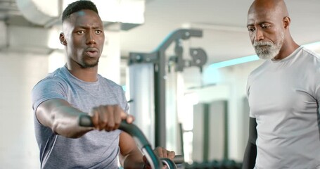 African American male trainer guiding client starting pedaling air bike in gym adjusting resistance