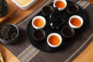 Chinese tea ceremony set with hot beverage in cups on wooden table