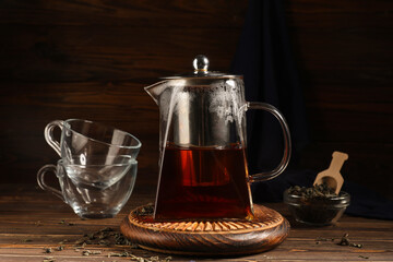 Teapot of hot black tea on wooden background, closeup