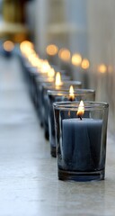 A line of lit candles in clear glass holders.