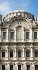 Fototapeta premium Ornate facade of a historical building, showcasing detailed carvings and symmetrical windows against a clear blue sky.