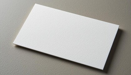 Blank white business card rests on a neutral gray surface.