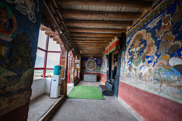 Naklejka premium Ladakh India,25 June 2025: Against the sweeping panorama of towering mountains and rolling clouds, the red painted monastery emerges as a breathtaking landmark. colorful walls, and golden decorations