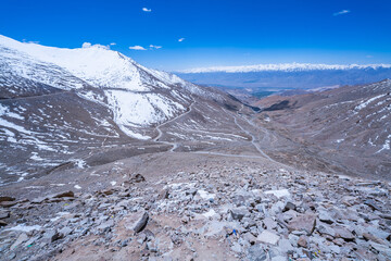 A rugged of Himalayan mountain ridge blanketed with patches of snow under a vivid blue sky, capturing the stark beauty and raw terrain of a high-altitude alpine landscape. nature dramatic textures.