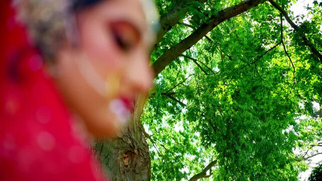 Bride with traditional jewelry and embroidered fabric on a green sunny day. 