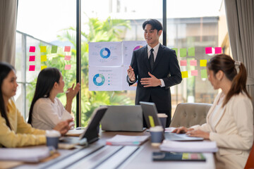 Asian businessman leading meeting with charts and sticky notes