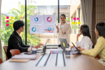 Asian businesswoman leading meeting with charts and pie graphs