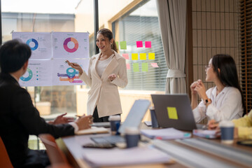 Asian businesswoman leading meeting, presenting charts and statistics to colleagues