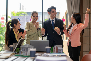 Real estate agents celebrating successful project with house model in office