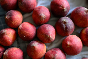 Beautiful tasty fresh peaches laying out on a table with bright red, orange and peach colors.