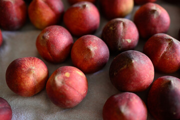 Beautiful tasty fresh peaches laying out on a table with bright red, orange and peach colors.