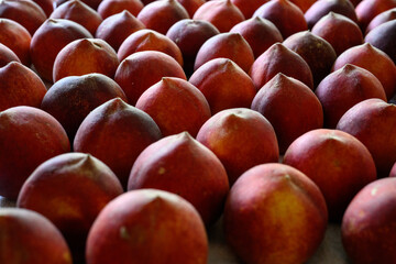 Beautiful tasty fresh peaches laying out on a table with bright red, orange and peach colors.