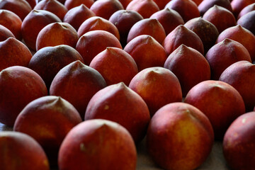 Beautiful tasty fresh peaches laying out on a table with bright red, orange and peach colors.
