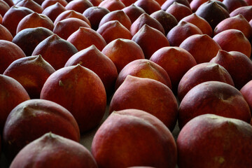 Beautiful tasty fresh peaches laying out on a table with bright red, orange and peach colors.