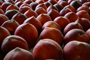 Beautiful tasty fresh peaches laying out on a table with bright red, orange and peach colors.