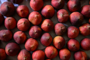 Beautiful tasty fresh peaches laying out on a table with bright red, orange and peach colors.