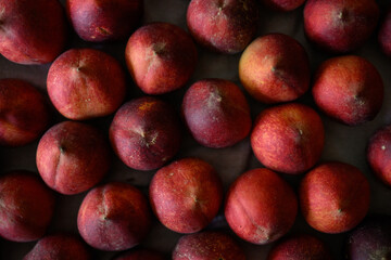 Beautiful tasty fresh peaches laying out on a table with bright red, orange and peach colors.