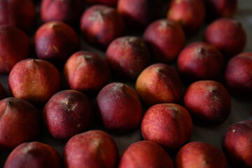 Beautiful tasty fresh peaches laying out on a table with bright red, orange and peach colors.