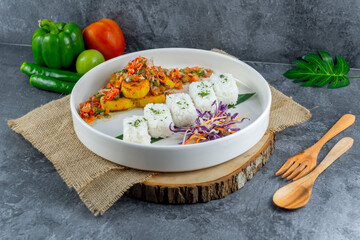 Balinese spicy fish served with rice and vegetables, topped with vibrant chili and spice salsa. This dish bursts with aromatic herbs and authentic island flavors.