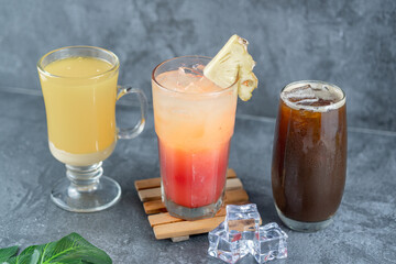 A trio of drinks: vibrant orange ginger, tropical pineapple mocktail, and honey long black coffee, each enticing with unique flavor and refreshing presentation.