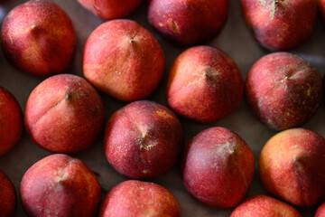 Beautiful tasty fresh peaches laying out on a table with bright red, orange and peach colors.