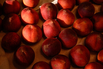 Beautiful tasty fresh peaches laying out on a table with bright red, orange and peach colors.