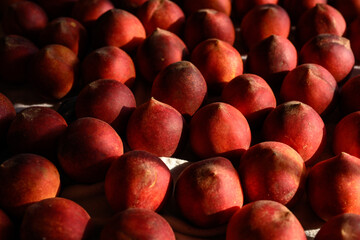 Beautiful tasty fresh peaches laying out on a table with bright red, orange and peach colors.